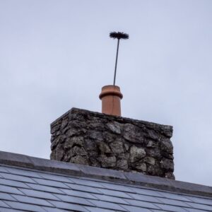 a stone chimney with a chimney sweeping brush sticking out of the top