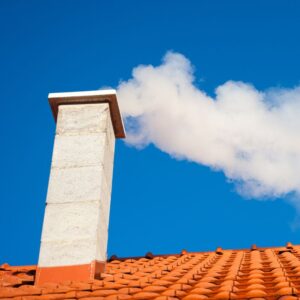 a white chimney on a red roof with smoke coming out the top
