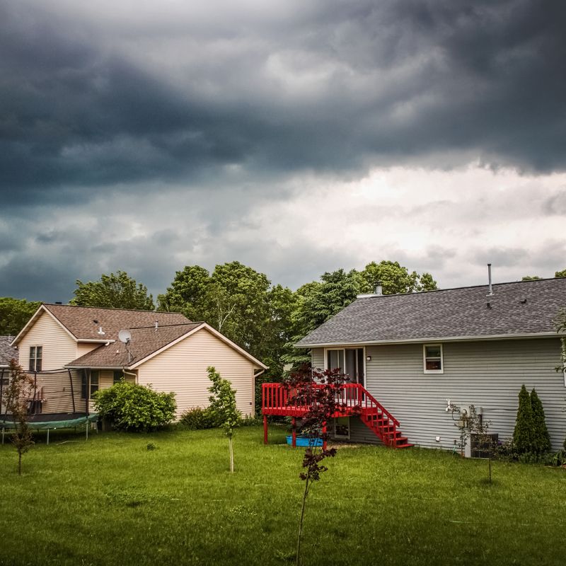two houses with storm clouds looming above them