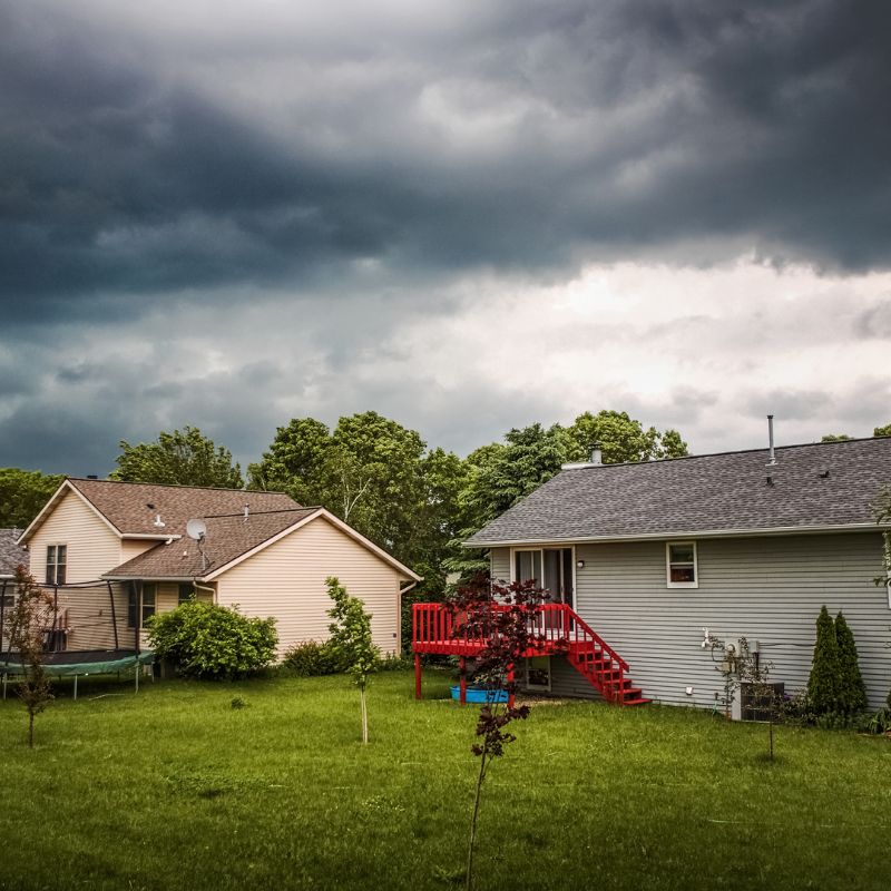 stock photo of storm coming by houses two houses with storm clouds looming above them