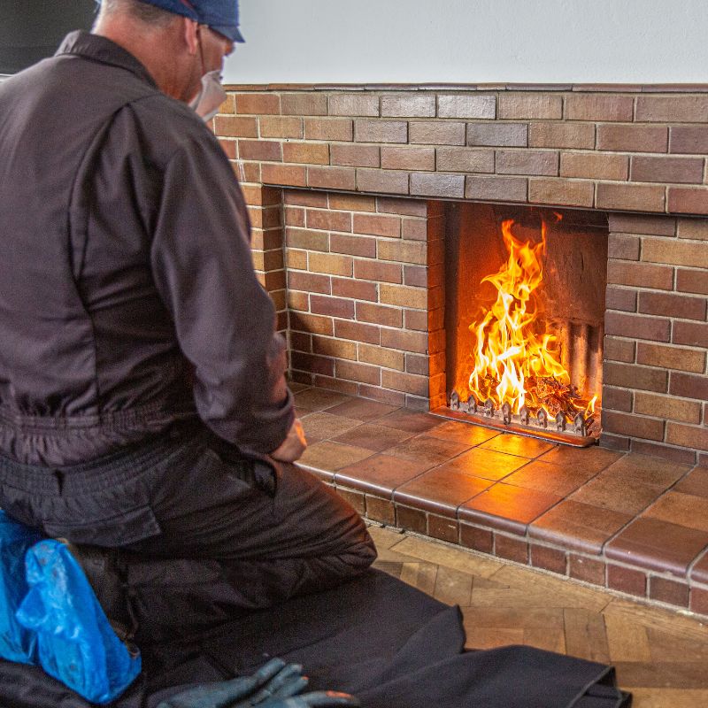 a chimney technician with blue booties checking on a fireplace
